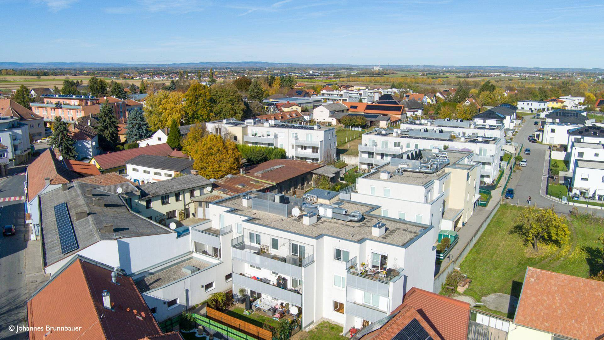 Weitläufige Luftaufnahme einer Wohngegend mit Blick auf die umliegende Landschaft und Dächer.