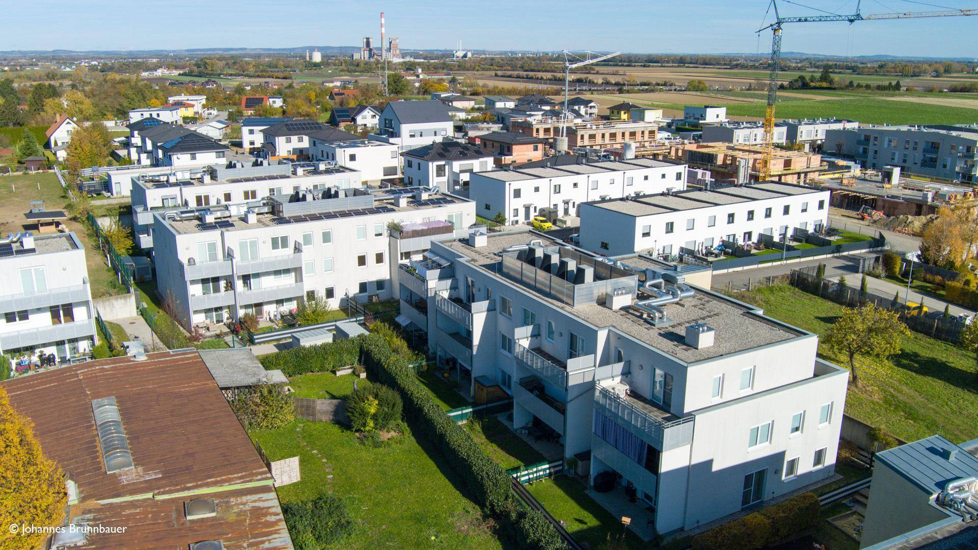 Weitläufige Luftaufnahme einer modernen Wohnsiedlung mit Neubauten und angrenzenden Bauprojekten.