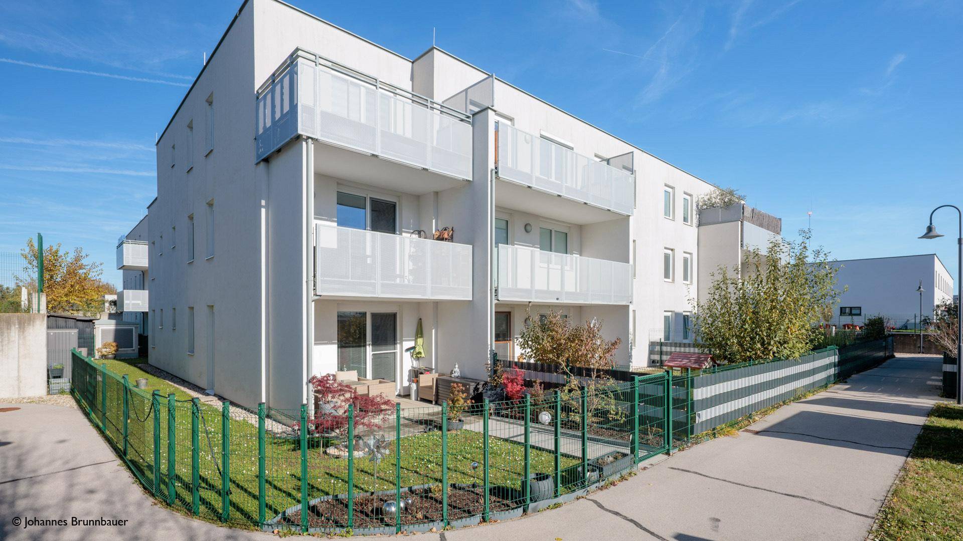 Moderne Wohnanlage mit gepflegten Gärten und Balkonen unter blauem Himmel.