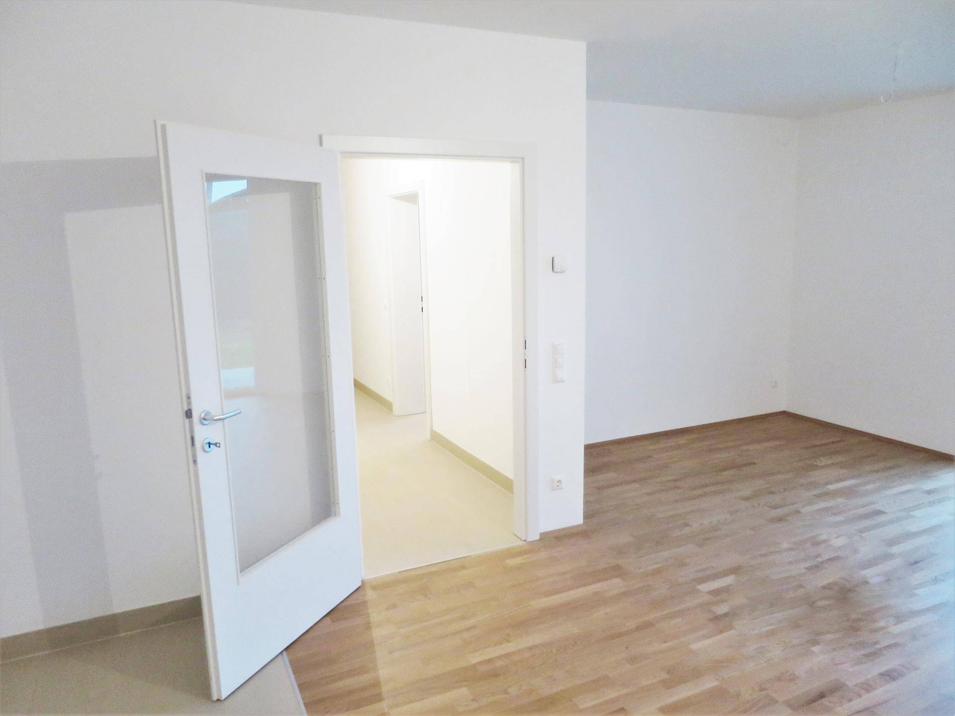 Heller Flur mit Parkettboden, der zu weiteren Räumen der Wohnung führt.