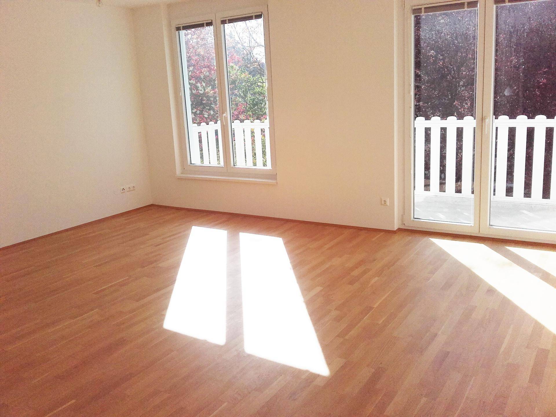 Lichtdurchfluteter Wohnbereich mit hellem Parkett und Blick ins Grüne.