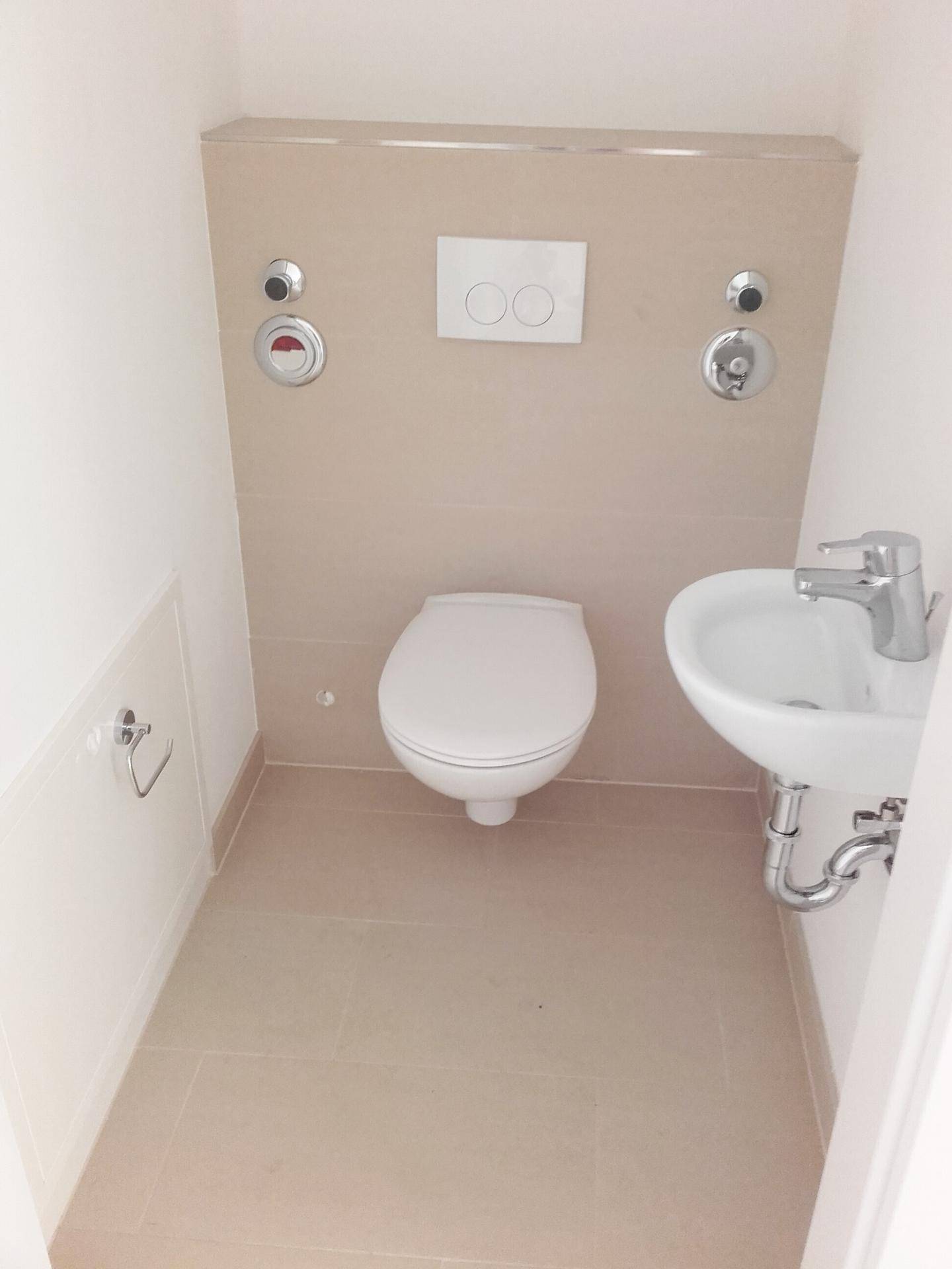 Modernes Gäste-WC mit wandhängendem WC und kleinem Waschbecken in hellen Fliesen.