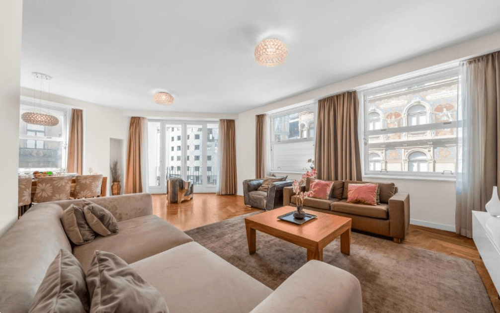 Weitläufiger Wohn- und Essbereich mit stilvollem Interieur, großen Fenstern und elegantem Fischgrätparkett.