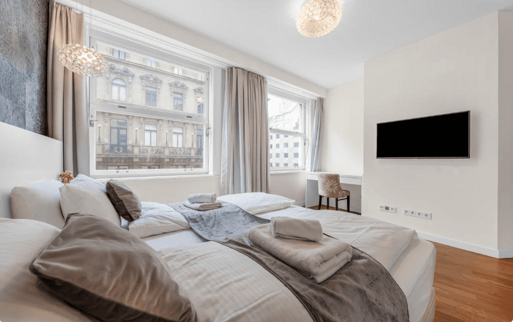 Gemütliches Schlafzimmer mit Holzboden, Schreibtisch und Blick auf die Stadt.