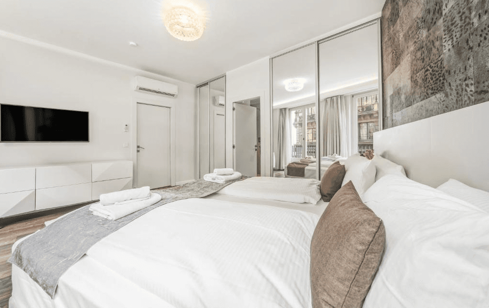 Modernes Schlafzimmer mit Spiegelschränken, Holzboden und Blick auf die Stadt.