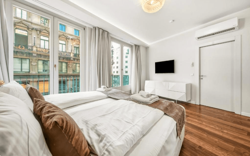 Helles Schlafzimmer mit Holzboden, Klimaanlage und Blick auf die Stadt.