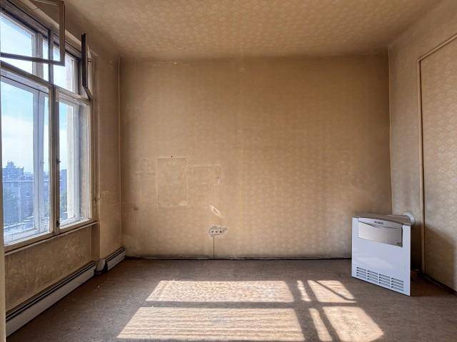 Schlafzimmer mit Teppichboden und einem Fenster, das viel Tageslicht hereinlässt und renoviert werden muss.