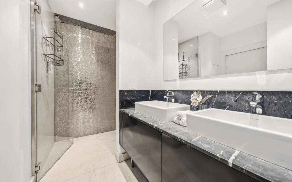 Modernes Badezimmer mit Doppelwaschbecken, Marmorplatte und begehbarer Dusche.
