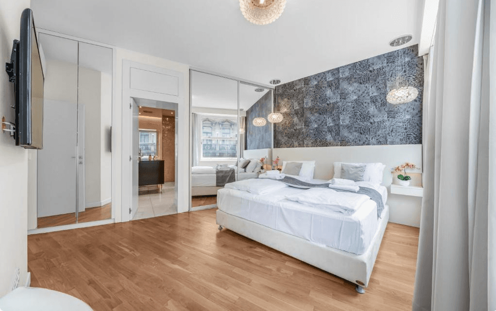 Helles Schlafzimmer mit Holzboden, Spiegelschränken und Zugang zum Badezimmer.