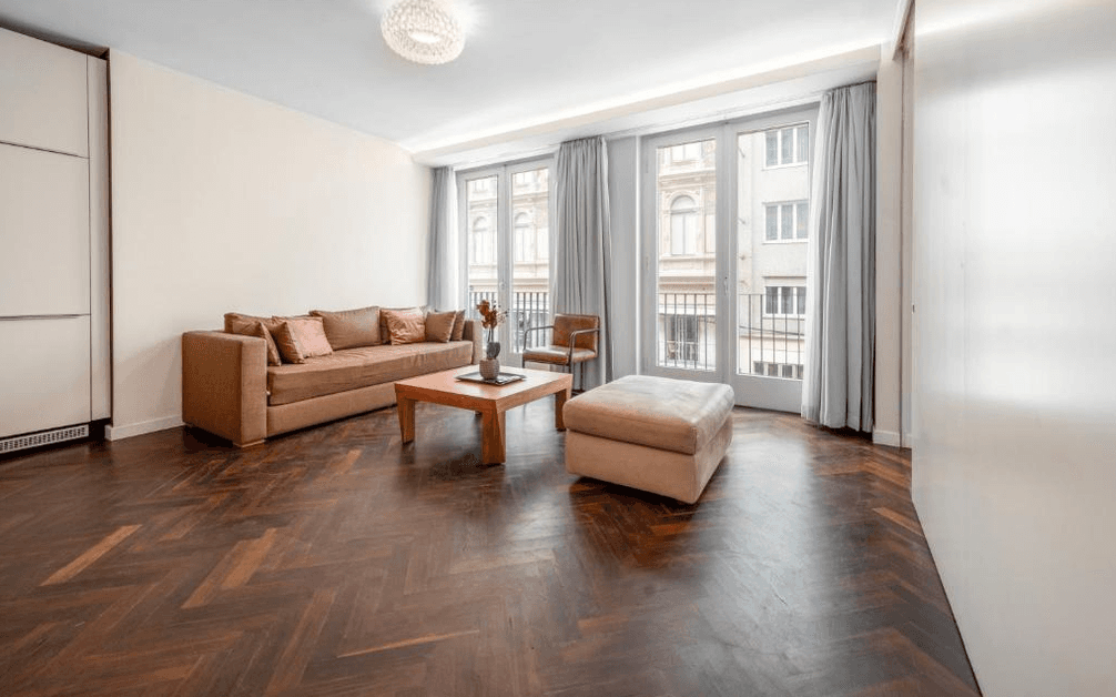 Geräumiges Wohnzimmer mit Fischgrätparkett, bequemer Couch und Zugang zum französischen Balkon.