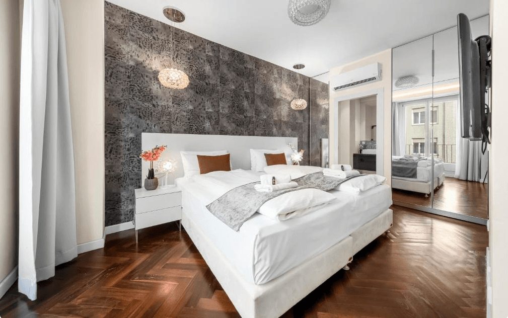 Elegantes Schlafzimmer mit großem Doppelbett, verspiegeltem Kleiderschrank und stilvoller Wandgestaltung.