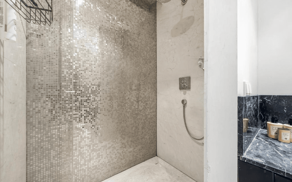 Moderne Dusche mit Mosaikfliesen und dunkler Marmorablage.
