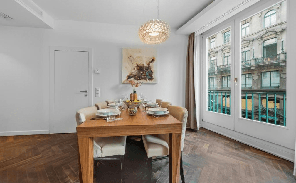 Eleganter Essbereich mit Holztisch, modernen Stühlen und Blick auf die historische Architektur der Stadt.