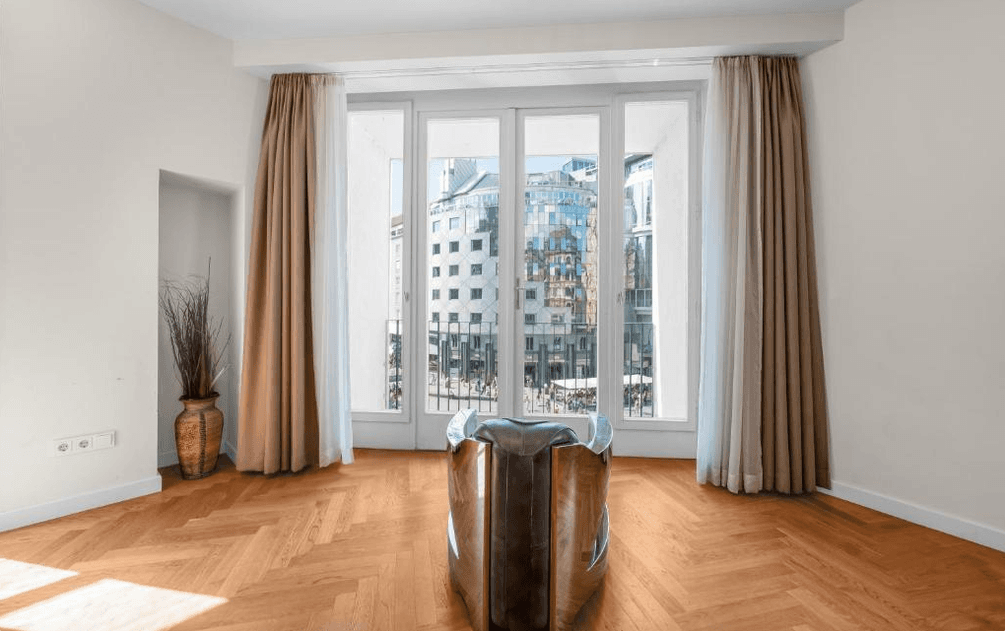 Heller Raum mit Fischgrätparkett und französischen Balkontüren, die einen weiten Blick auf die Stadt bieten.