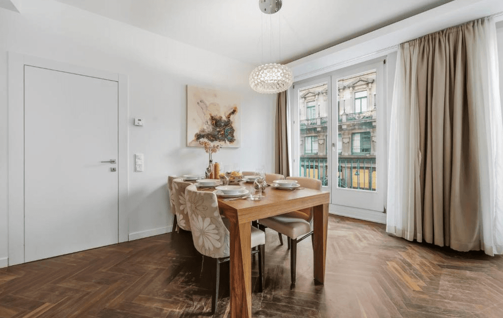 Heller Essbereich mit Holztisch, modernen Stühlen und Blick auf die historische Architektur der Stadt.
