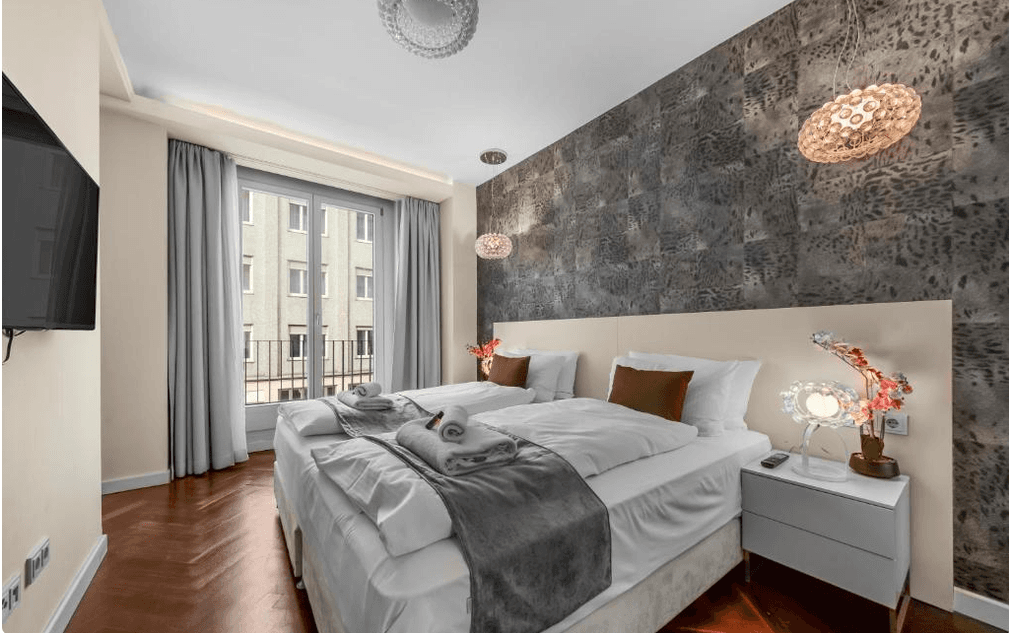 Komfortables Schlafzimmer mit Doppelbett, stilvoller Wandgestaltung und Zugang zu einem französischen Balkon.