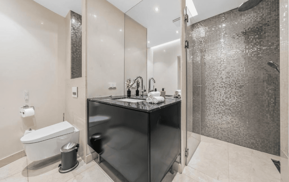 Modernes Badezimmer mit wandhängendem WC, Einzelwaschbecken und geräumiger begehbarer Dusche mit Mosaikfliesen.