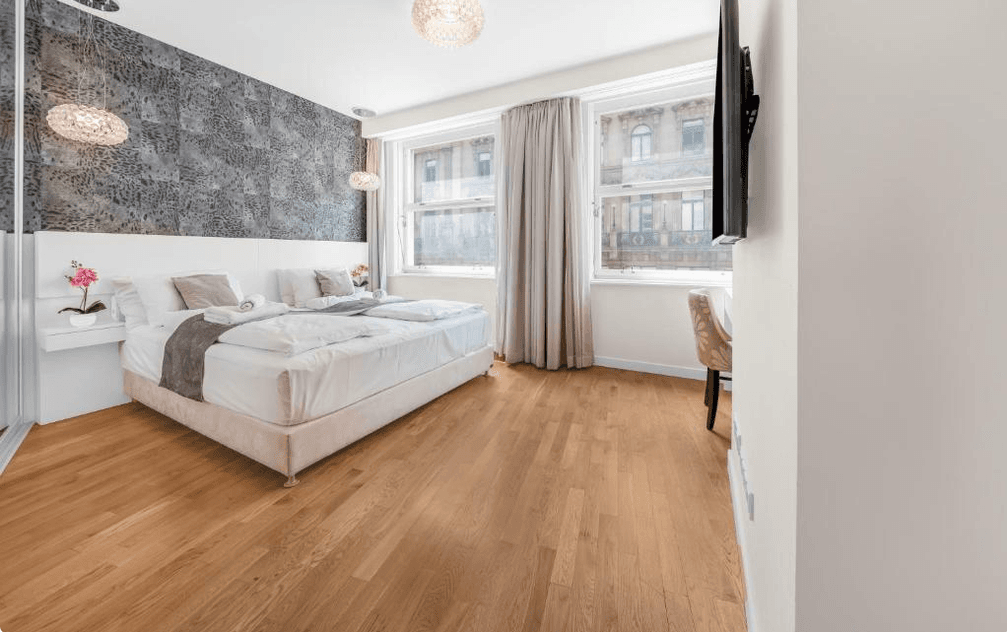 Geräumiges Schlafzimmer mit Holzboden, dekorativer Wand und Blick auf die Stadt.