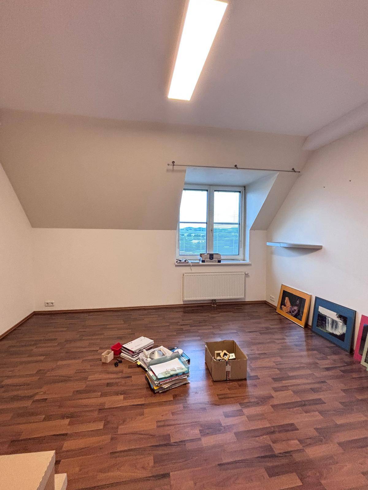Heller Raum im Dachgeschoss mit Holzboden, einem Fenster und viel natürlichem Licht.
