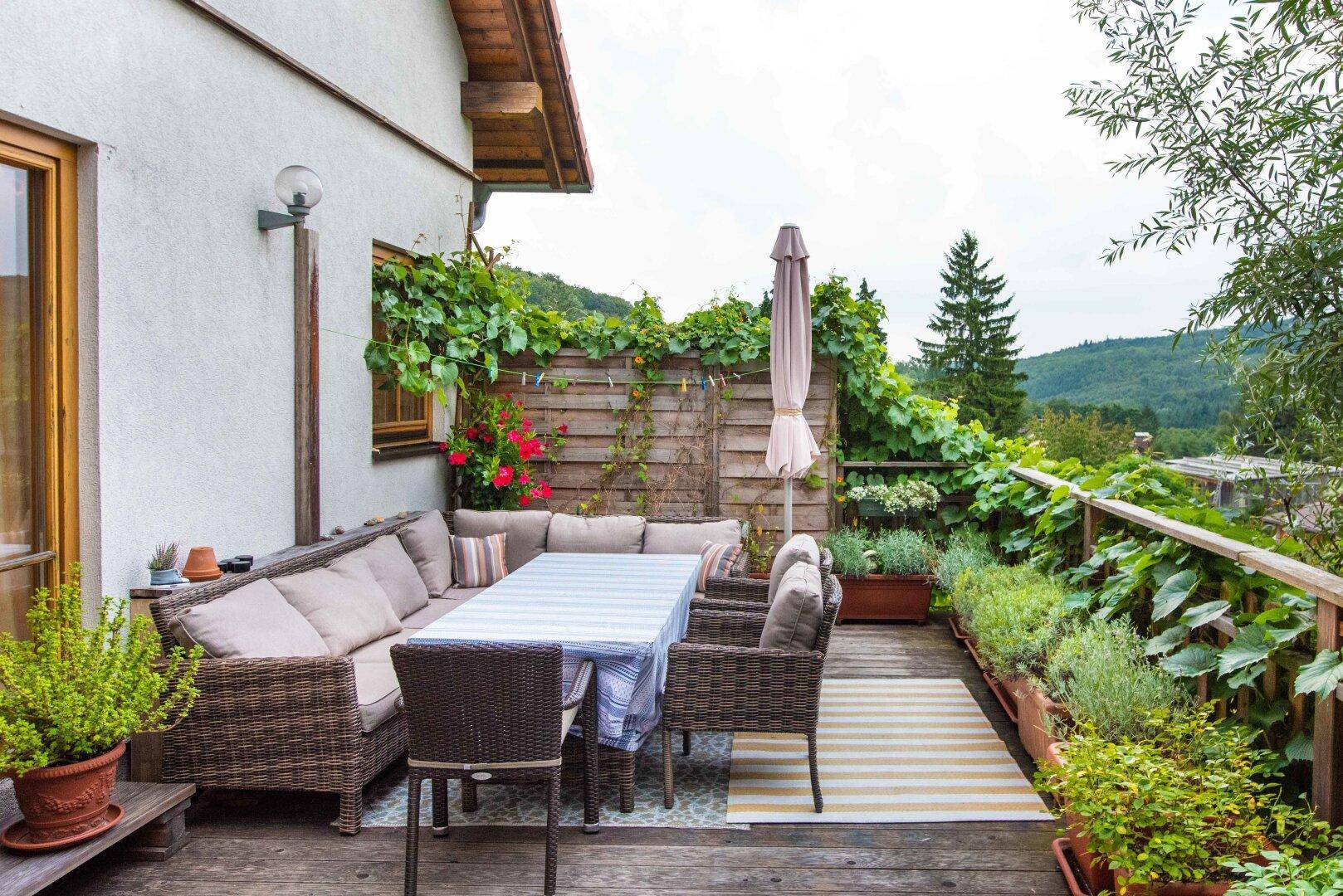 Geräumige Holzterrasse mit bequemen Gartenmöbeln und weitem Blick ins Grüne.