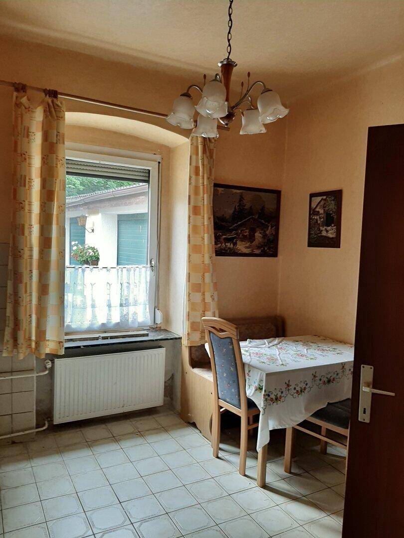 Gemütlicher Essbereich mit kleinem Tisch, Stühlen und Fenster mit Blick nach draußen.
