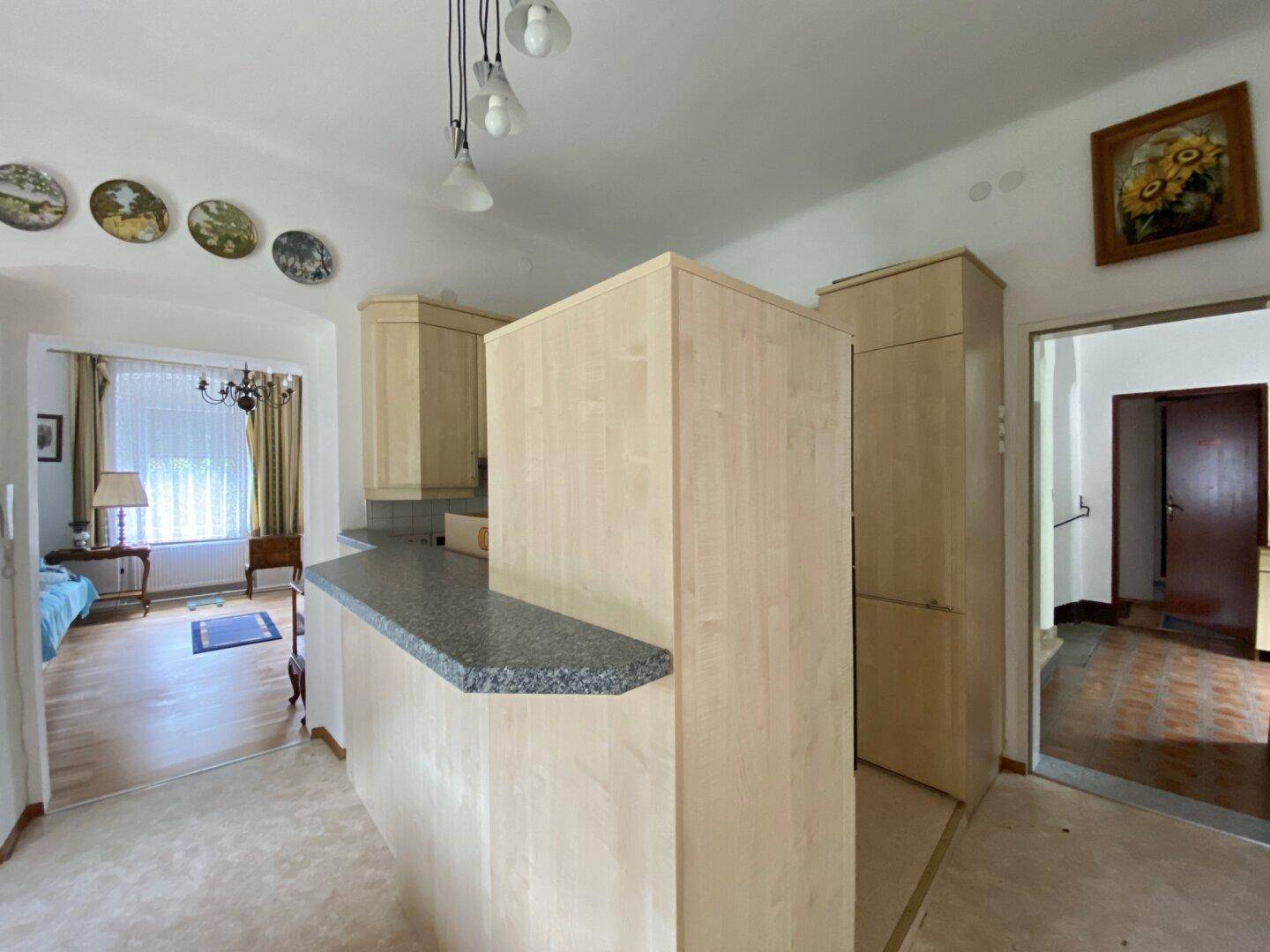 Küchenzeile mit heller Holzverkleidung und Granitplatte, offen zum angrenzenden Wohnbereich.