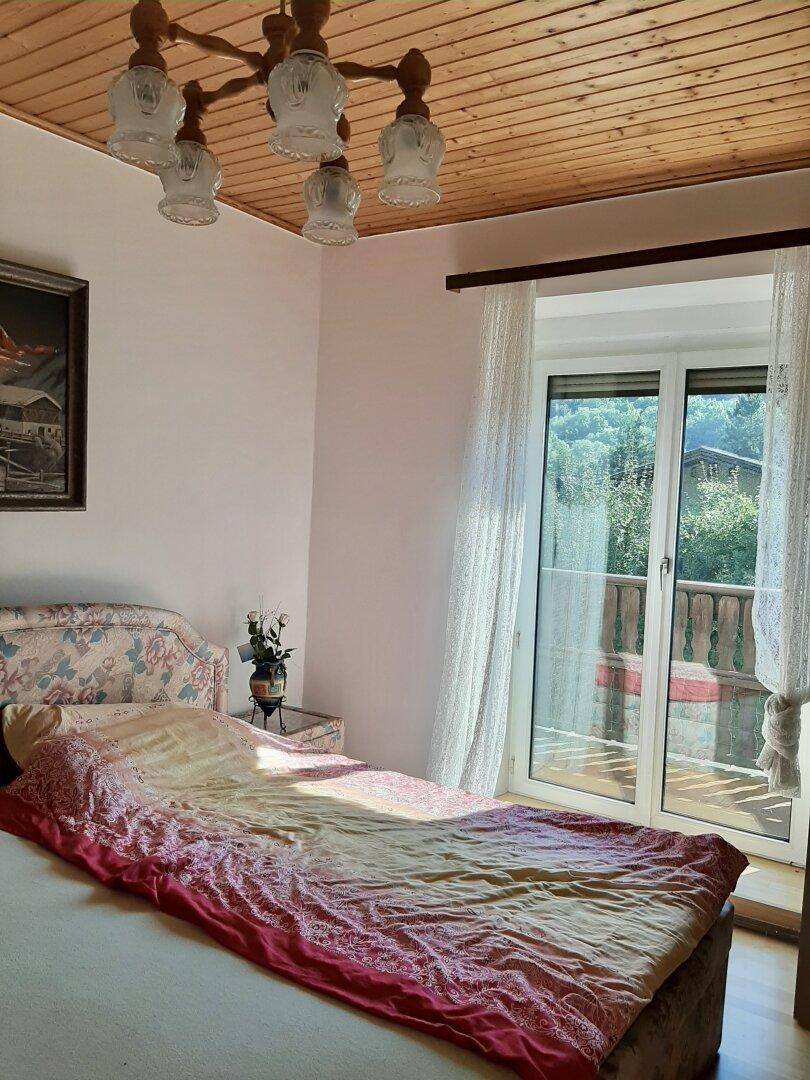 Schlafzimmer mit Doppelbett, Holzdecke und Zugang zu einem Balkon mit Aussicht.