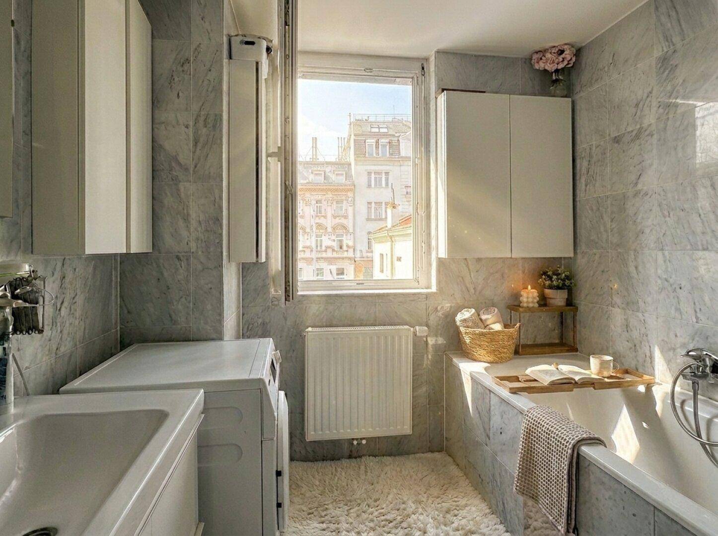 Helles Badezimmer mit Badewanne, Waschmaschine und Fenster mit Blick auf die Stadt.