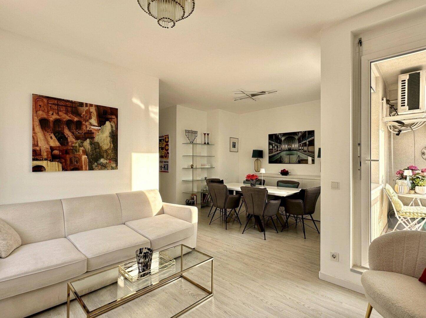 Heller, offener Wohn- und Essbereich mit modernem Design, hellem Boden und Zugang zum Balkon.