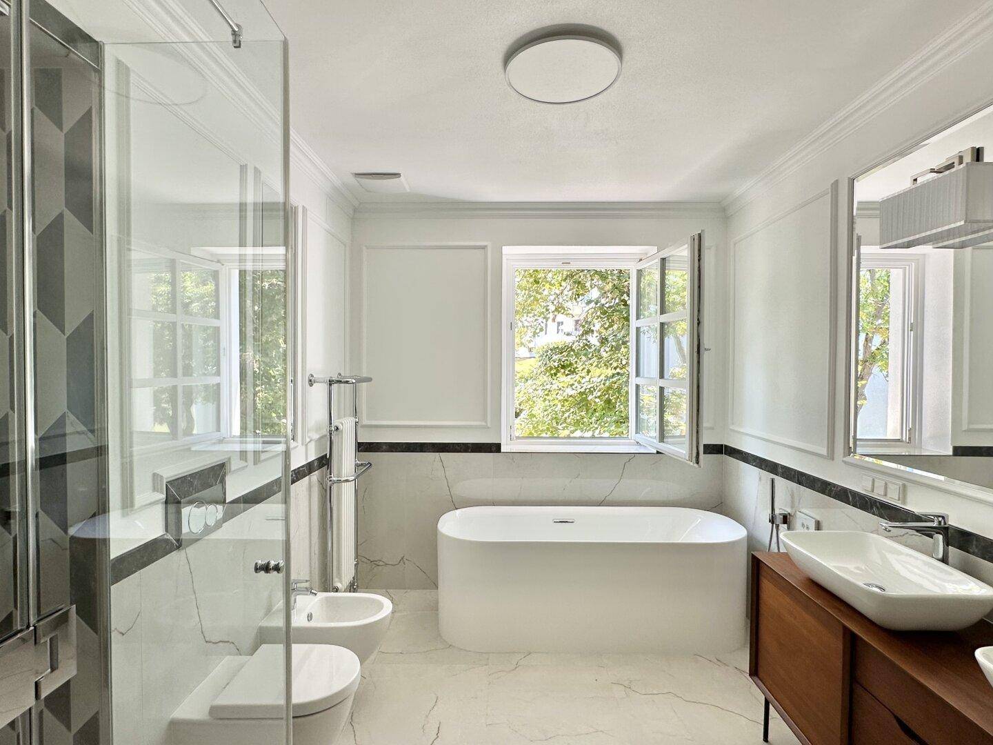 Modernes Badezimmer mit freistehender Badewanne, Dusche, Bidet und eleganten Marmorfliesen.