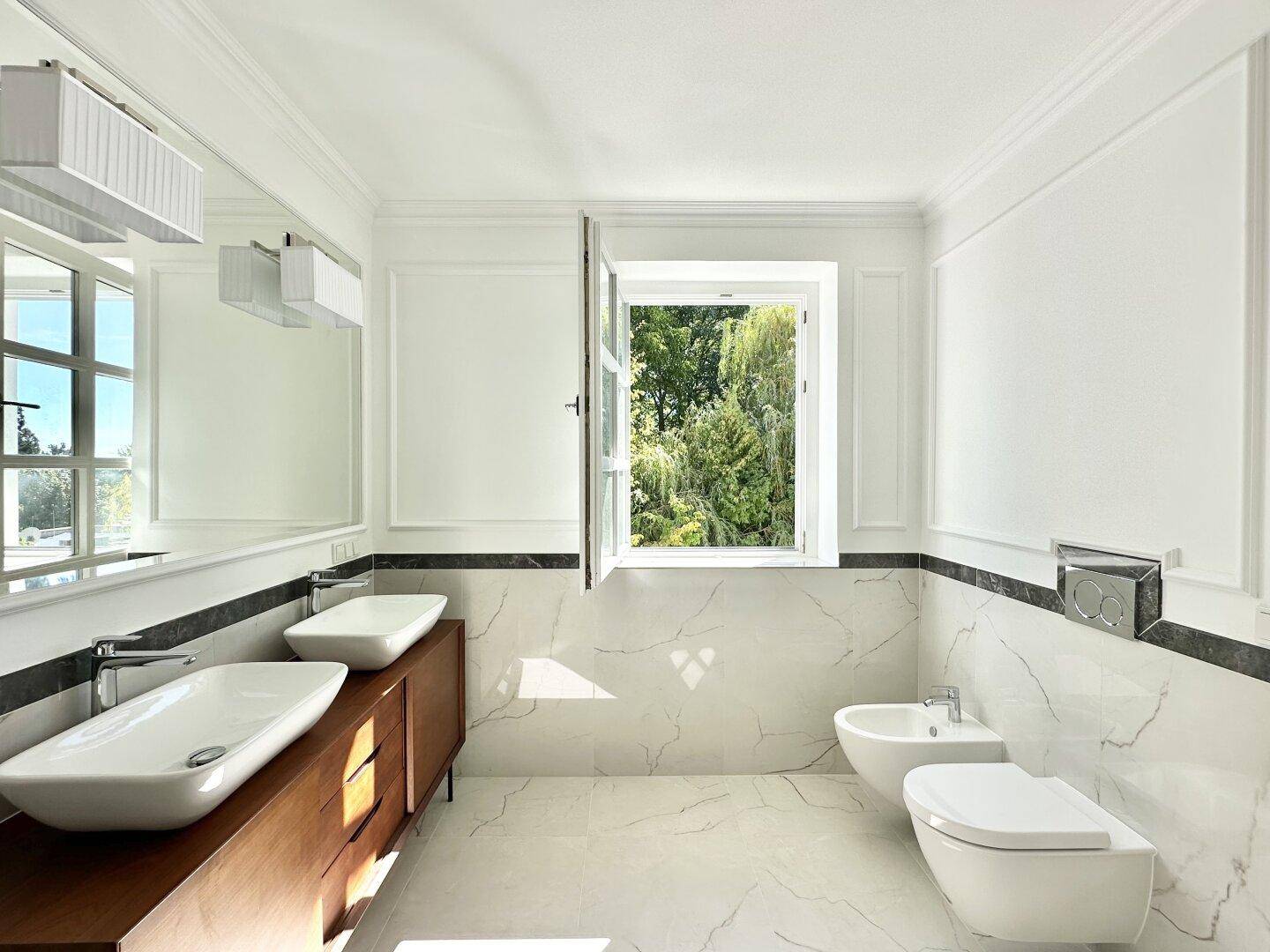 Elegantes Badezimmer mit Doppelwaschbecken, Bidet, Wand-WC und luxuriösen Marmorfliesen.