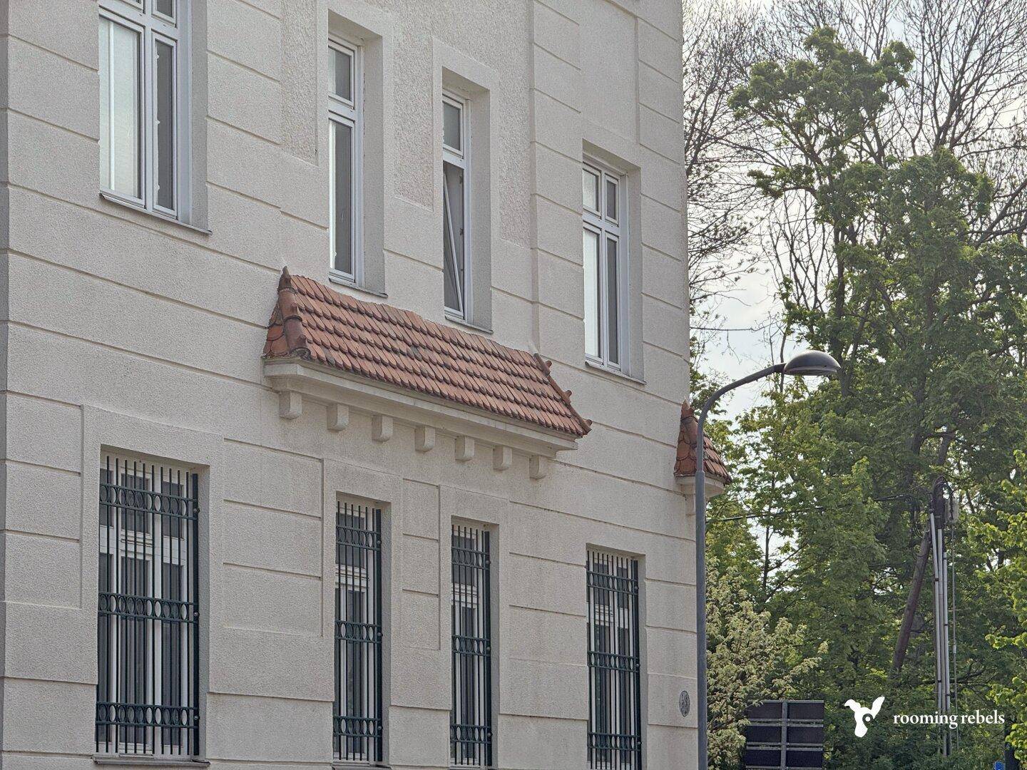 Gut erhaltene Fassade eines älteren Gebäudes mit klassischen Fenstern und schmiedeeisernen Gittern.