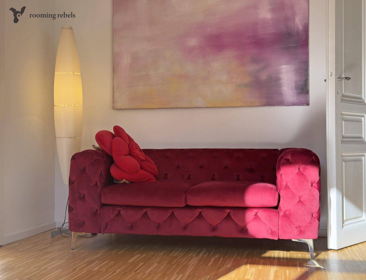 Gemütliches Wohnzimmer mit einem auffälligen pinkfarbenen Sofa und einem modernen Stehlampen-Design.