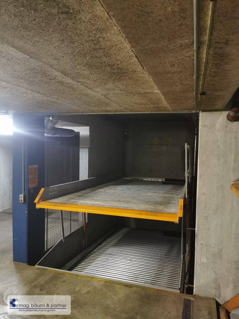 Ein weiteres Doppelparker-System in der Tiefgarage, mit gelben Akzenten und Metallkonstruktion.