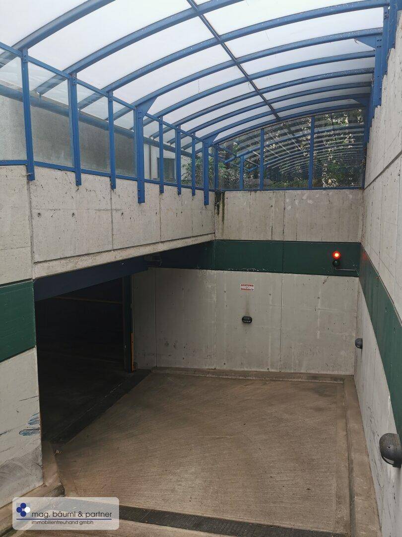 Ende der Tiefgaragenrampe mit einem roten Signallicht vor dem Eingang zum Parkbereich.