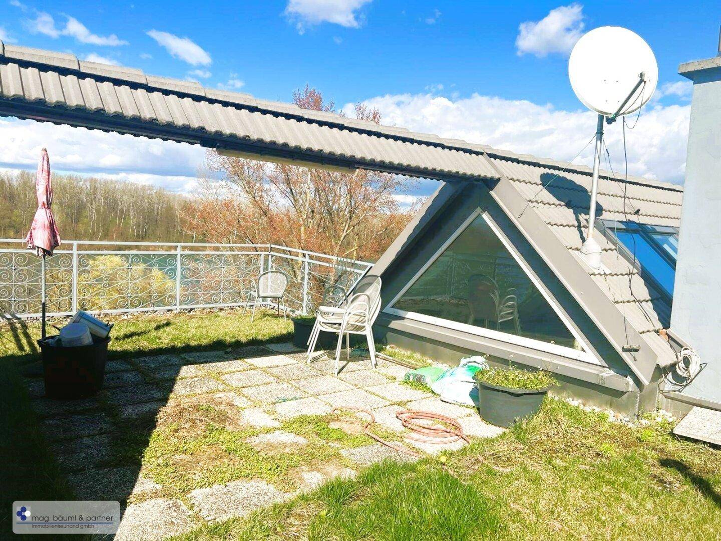 Dachterrasse mit Fliesenboden, Satellitenschüssel und einem schrägen Dachfenster, das Licht ins Innere bringt.