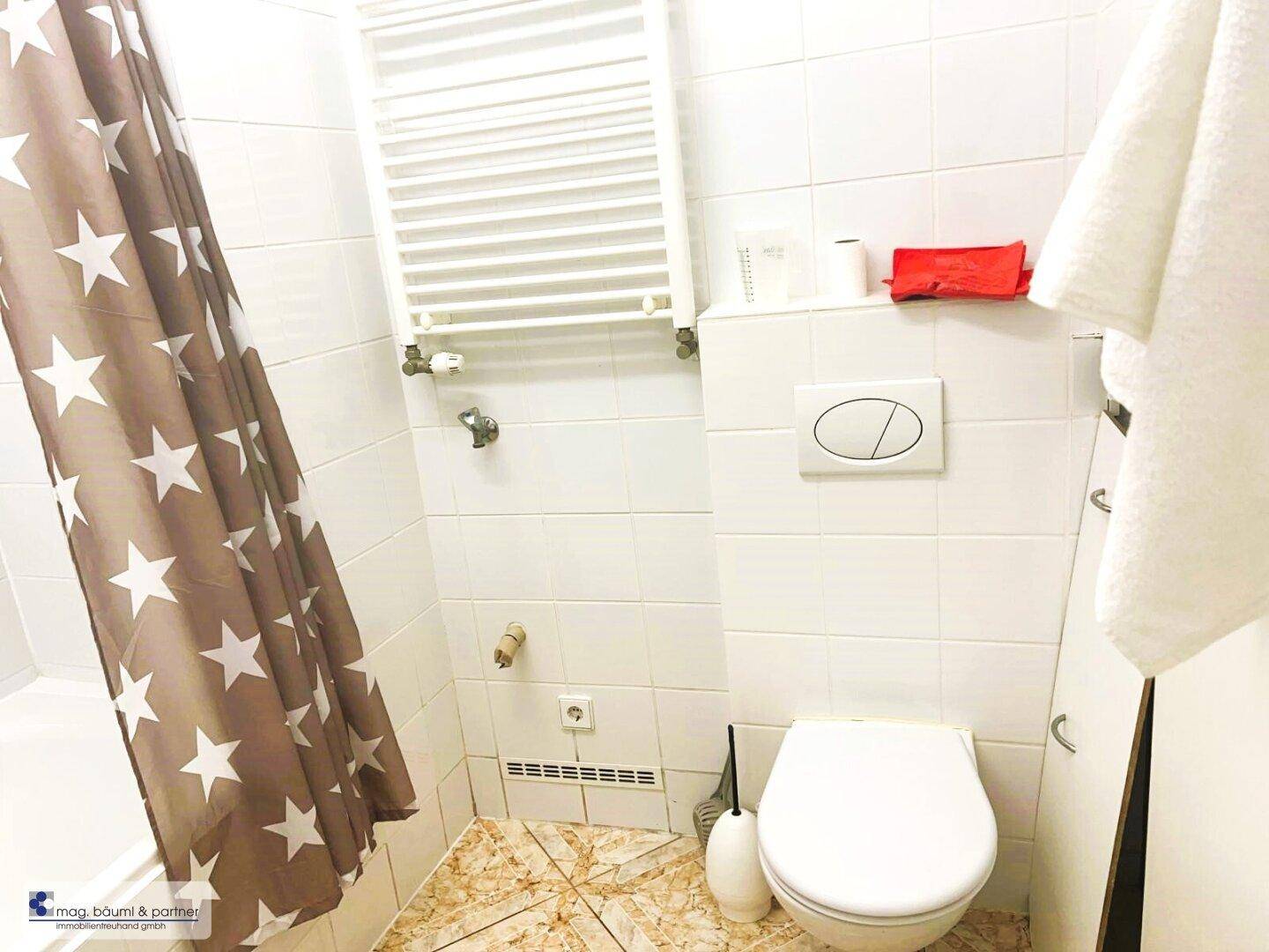 Separates WC mit Toilette, beheiztem Handtuchhalter und einem Duschvorhang mit Sternenmuster.
