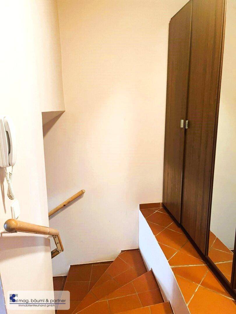 Treppenaufgang mit Fliesenboden und einem integrierten Spiegelschrank, der zusätzlichen Stauraum bietet.