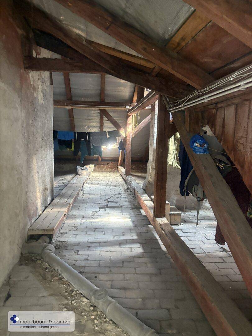 Geräumiger Dachboden mit sichtbaren Holzbalken, Ziegelboden und viel Stauraum.