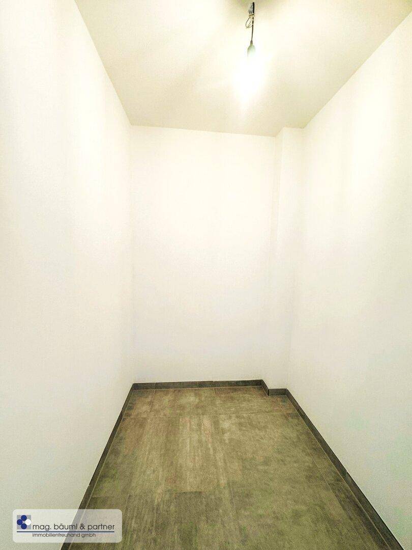 Kleiner Abstellraum mit dunklem Fliesenboden und weißen Wänden, ideal für zusätzlichen Stauraum.