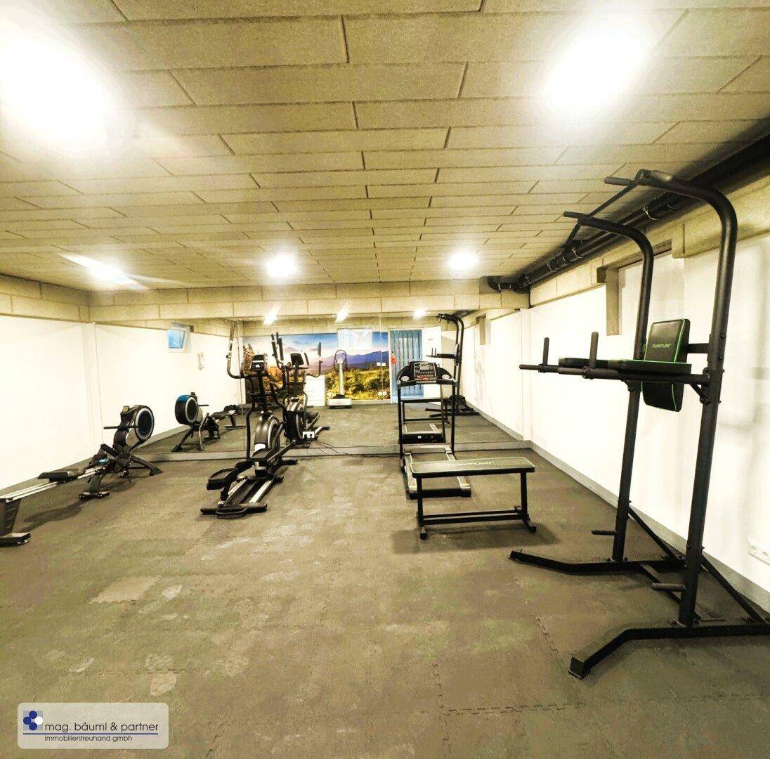 Gut ausgestatteter Fitnessraum mit verschiedenen Trainingsgeräten und einer motivierenden Wandgestaltung.