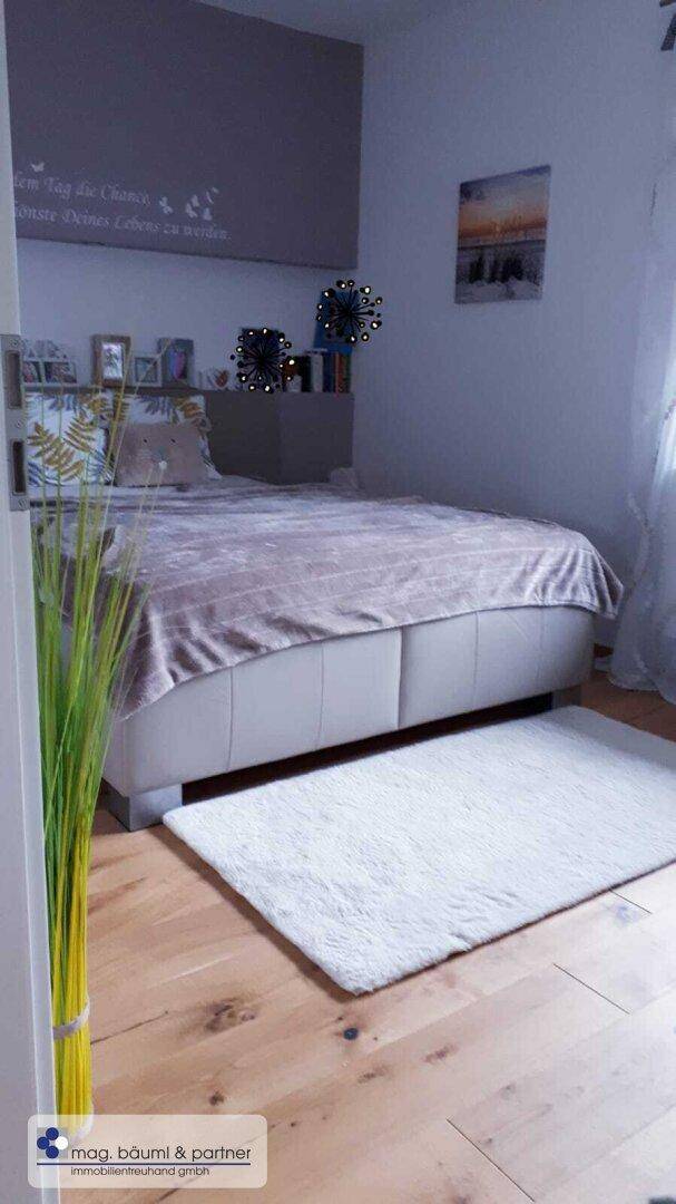 Schlafzimmer mit Holzboden, großem Bett und dezenter Wandgestaltung.