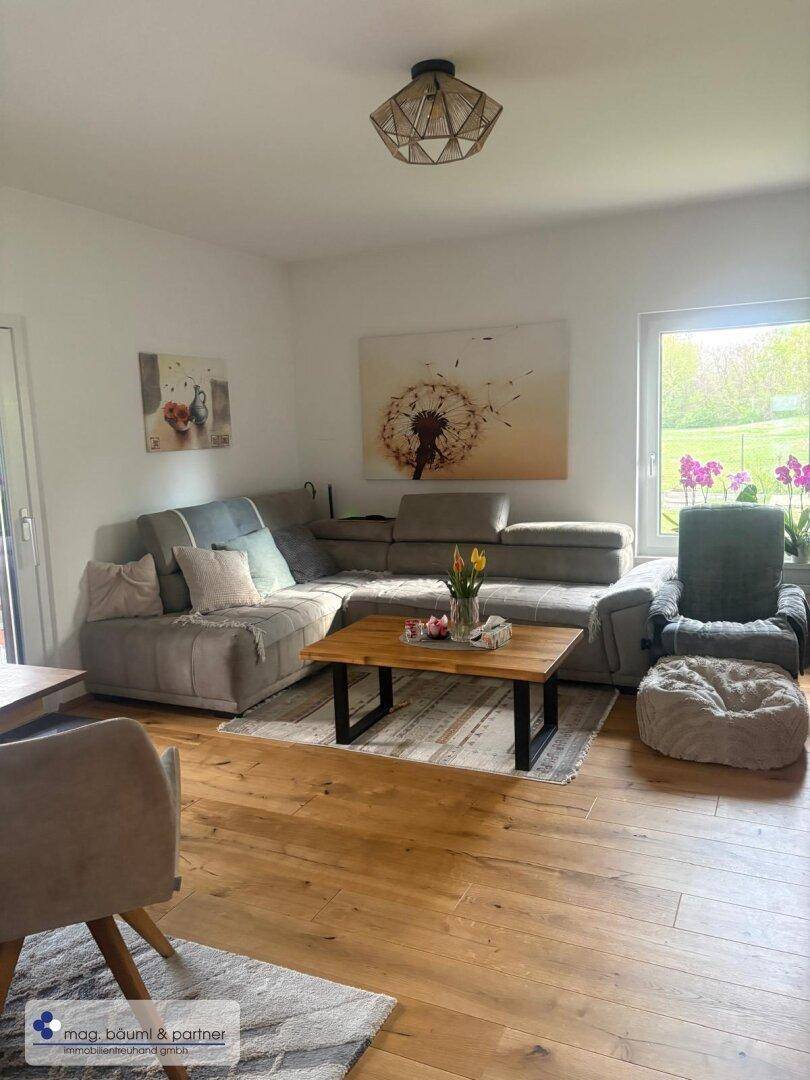 Gemütliches Wohnzimmer mit großem Ecksofa, Holzboden und Blick ins Grüne.