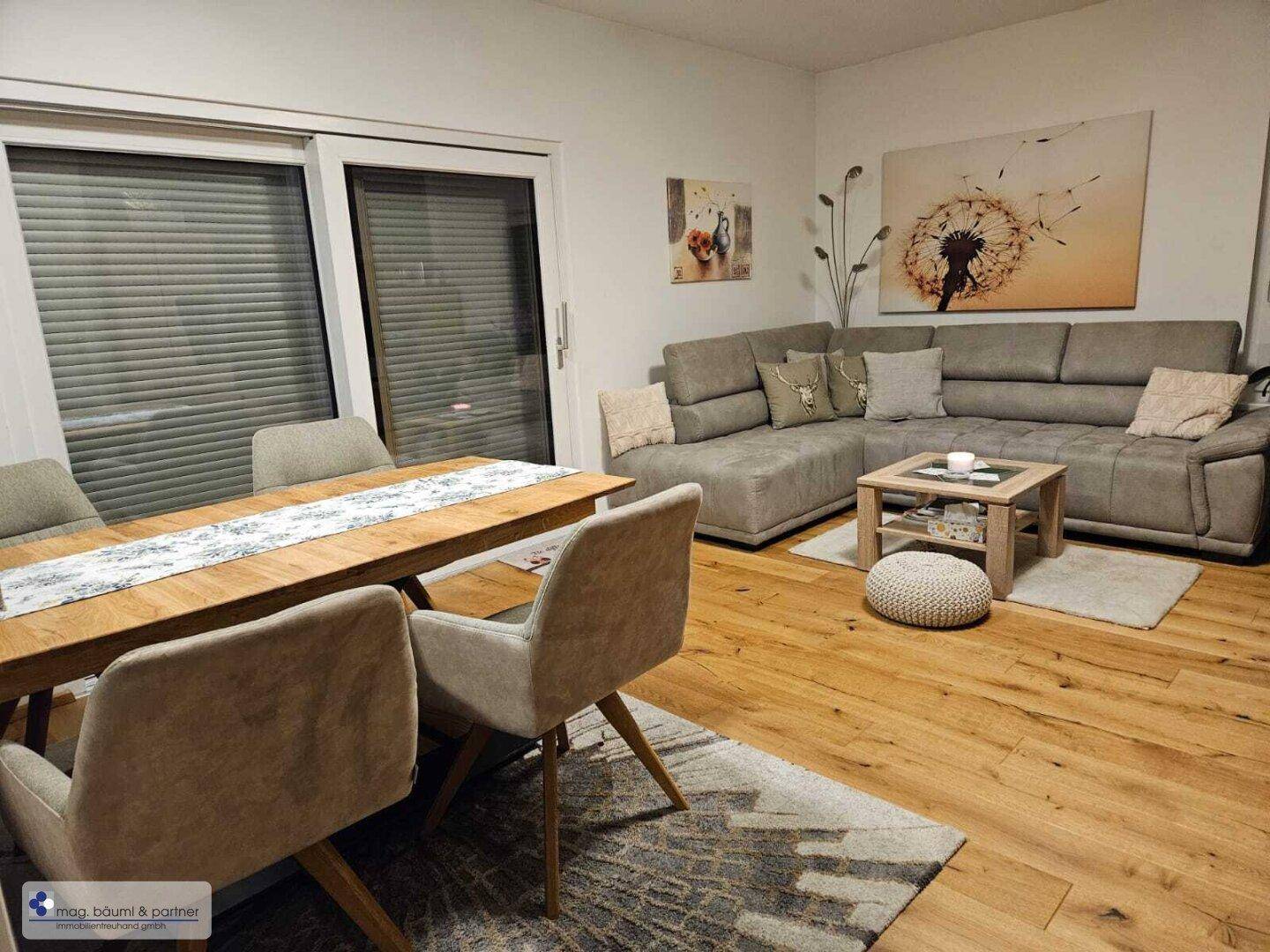 Offener Wohn- und Essbereich mit Holzboden, großem Esstisch und bequemer Sitzecke.