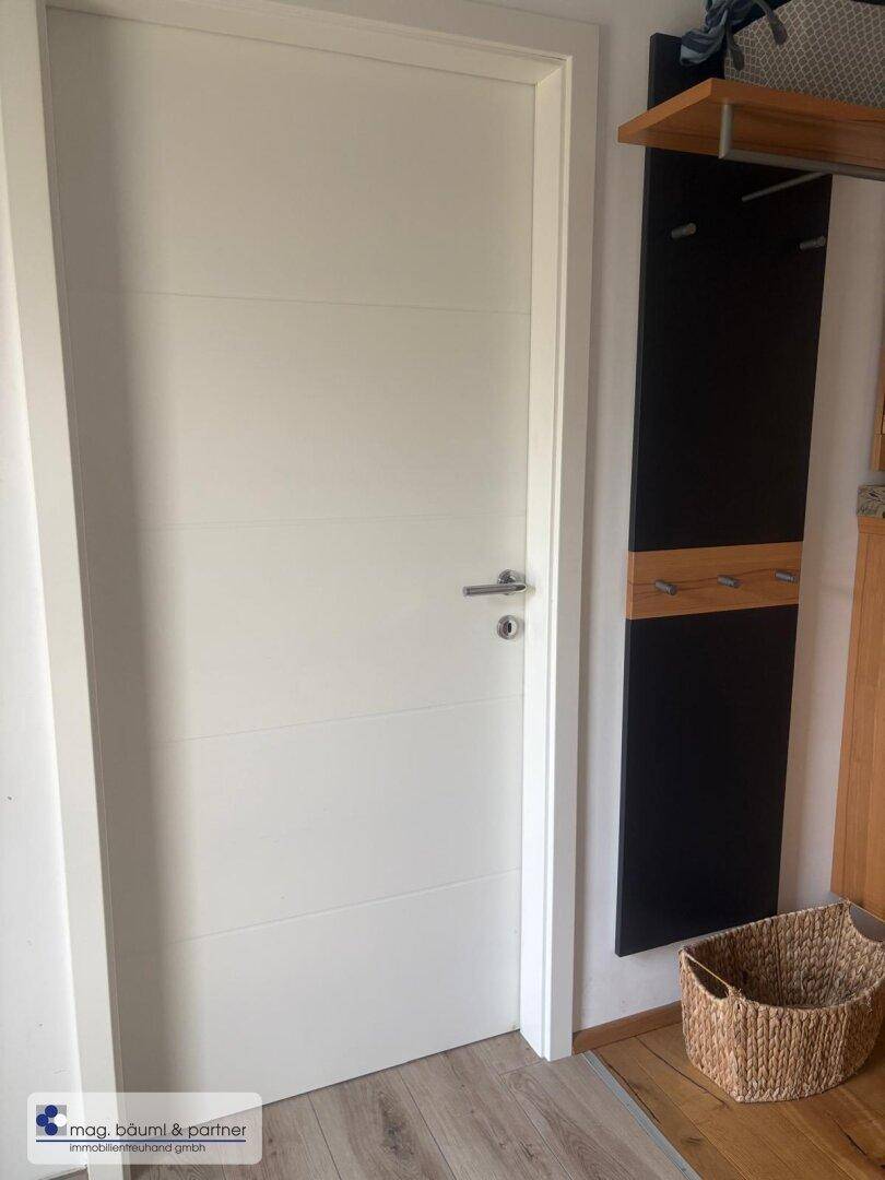 Moderner Flur mit weißer Tür, Holzboden und praktischer Garderobe.