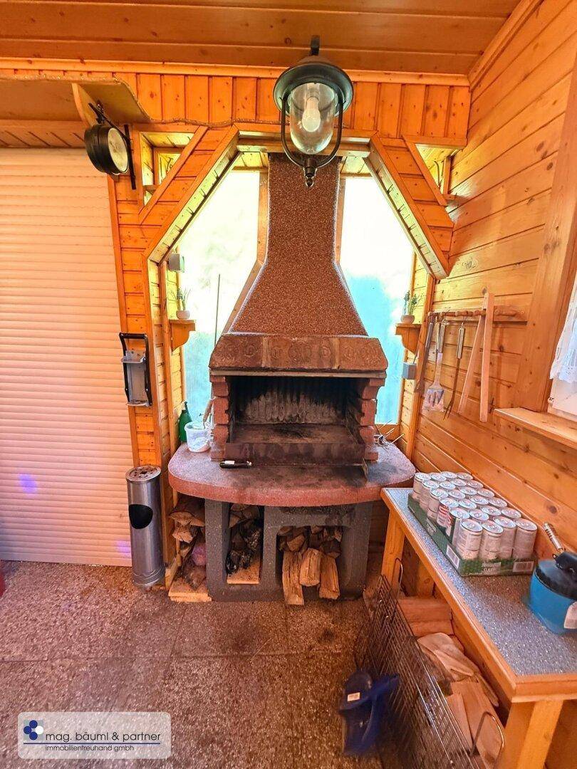 Überdachter Außenbereich mit gemauertem Grill und Holzvertäfelung.