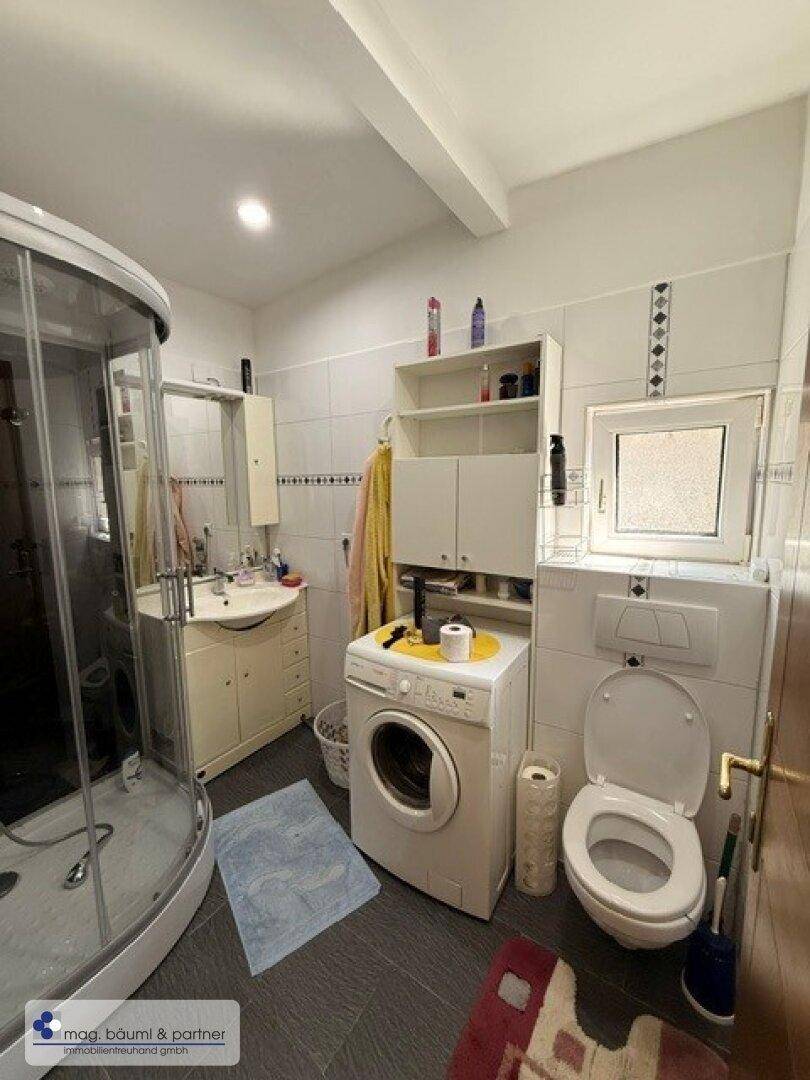 Modernes Badezimmer mit Duschkabine, Waschmaschine und Fenster.