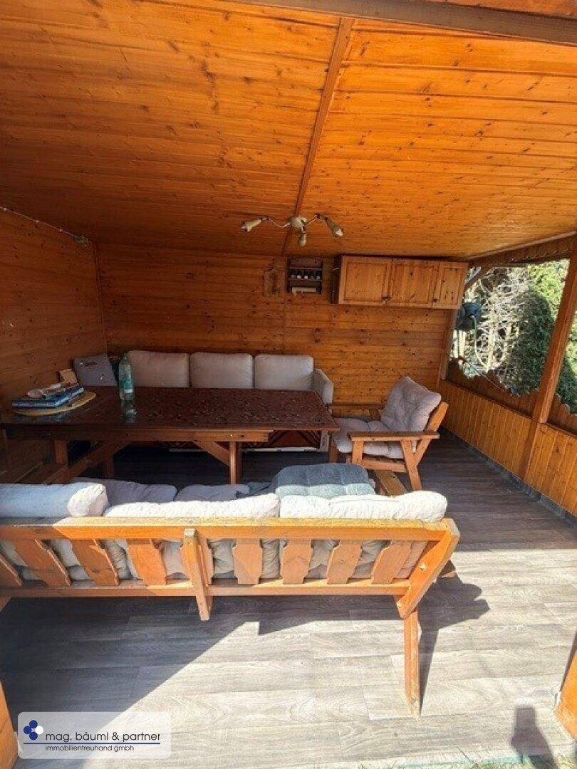 Überdachte Holzterrasse mit Sitzgelegenheiten und Blick ins Grüne.