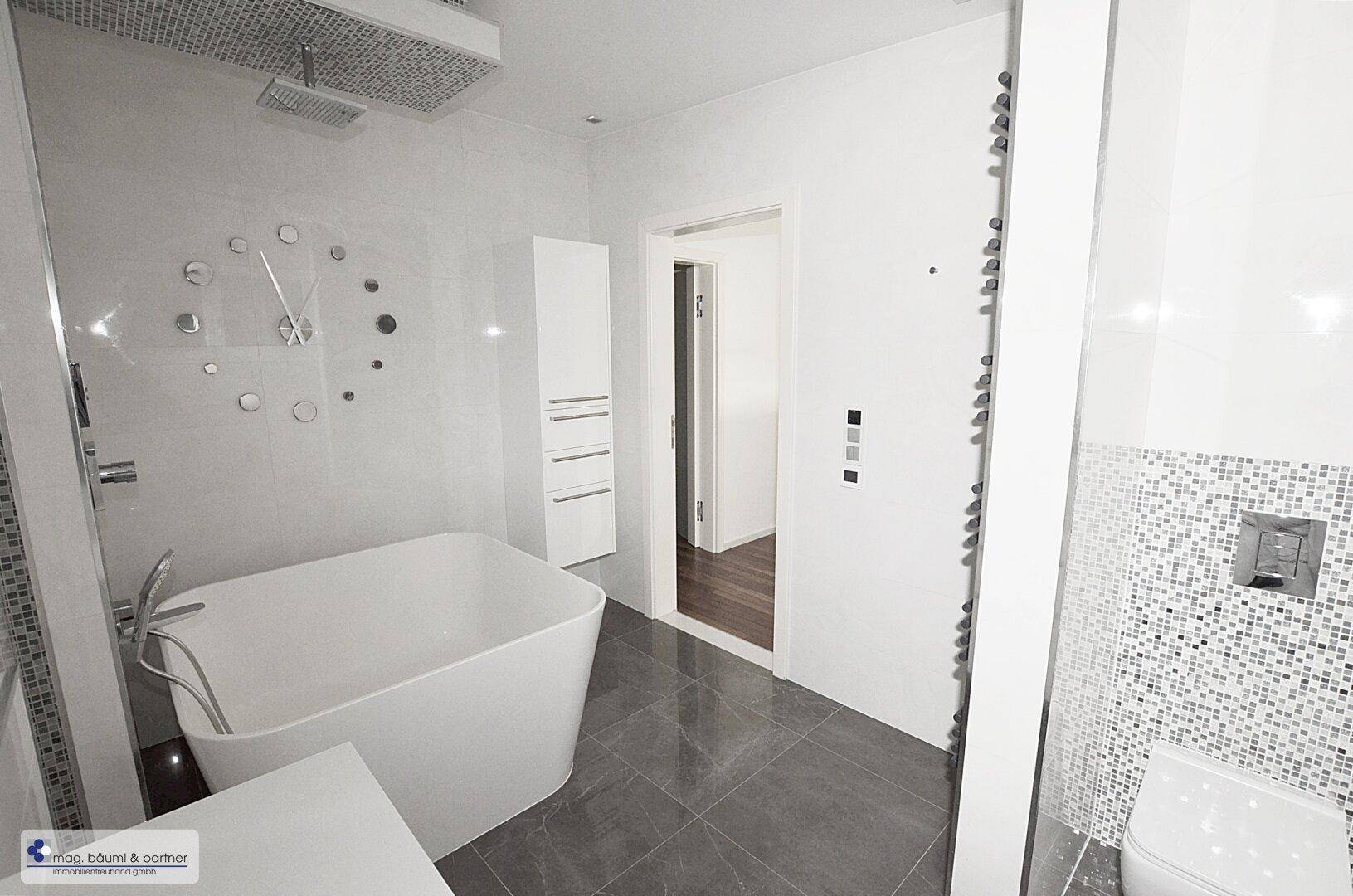 Luxuriöses Badezimmer mit freistehender Badewanne, Regendusche und beheiztem Handtuchhalter.