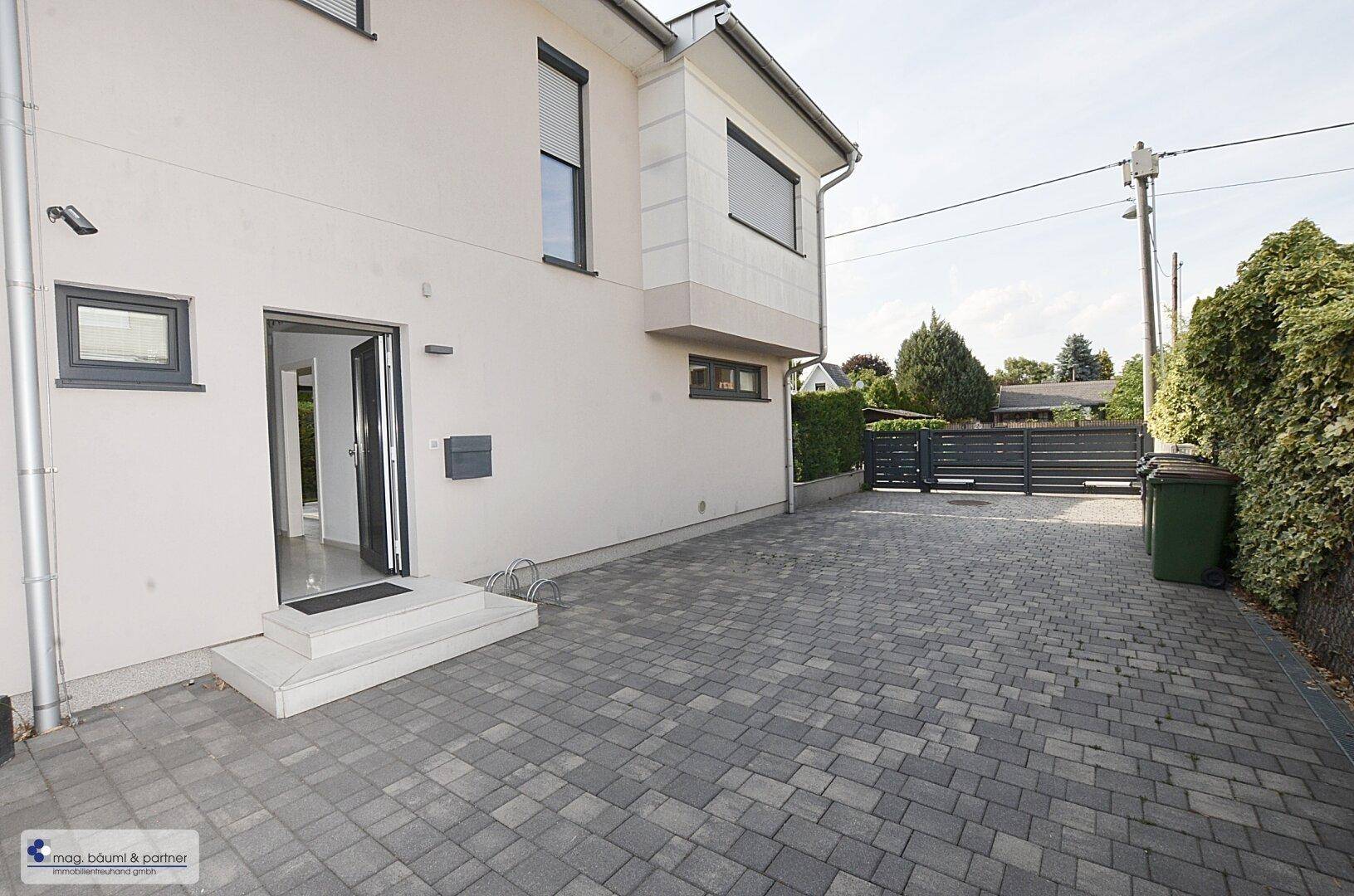 Eingangsbereich des Hauses mit gepflasterter Zufahrt und moderner Fassade.